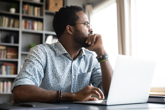 Man sitting with laptop while deep in thought